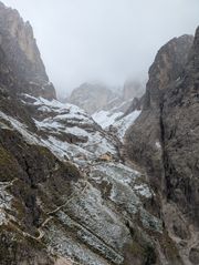 Rifugio Bergamo emerging from the mist in a snow-covered valley.