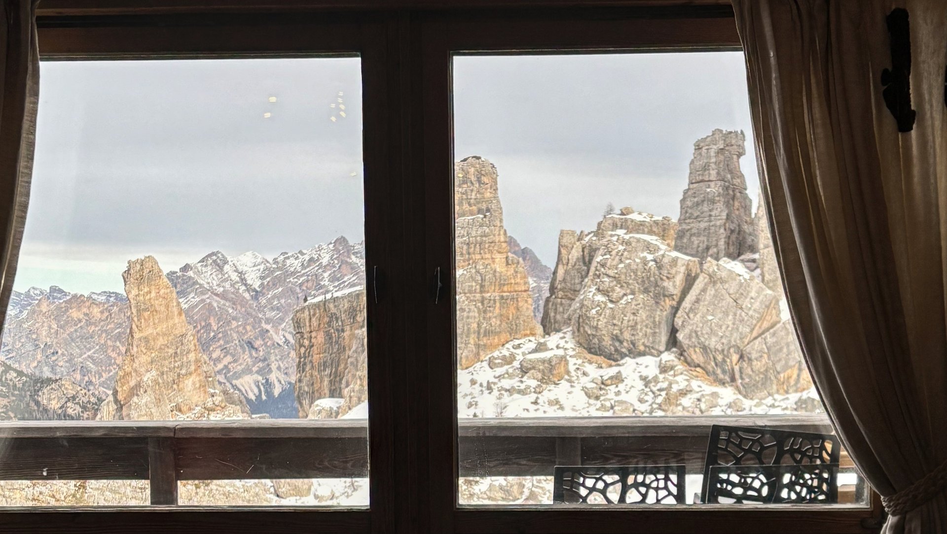 The Cinque Torri rock towers seen through a wooden hut window.
