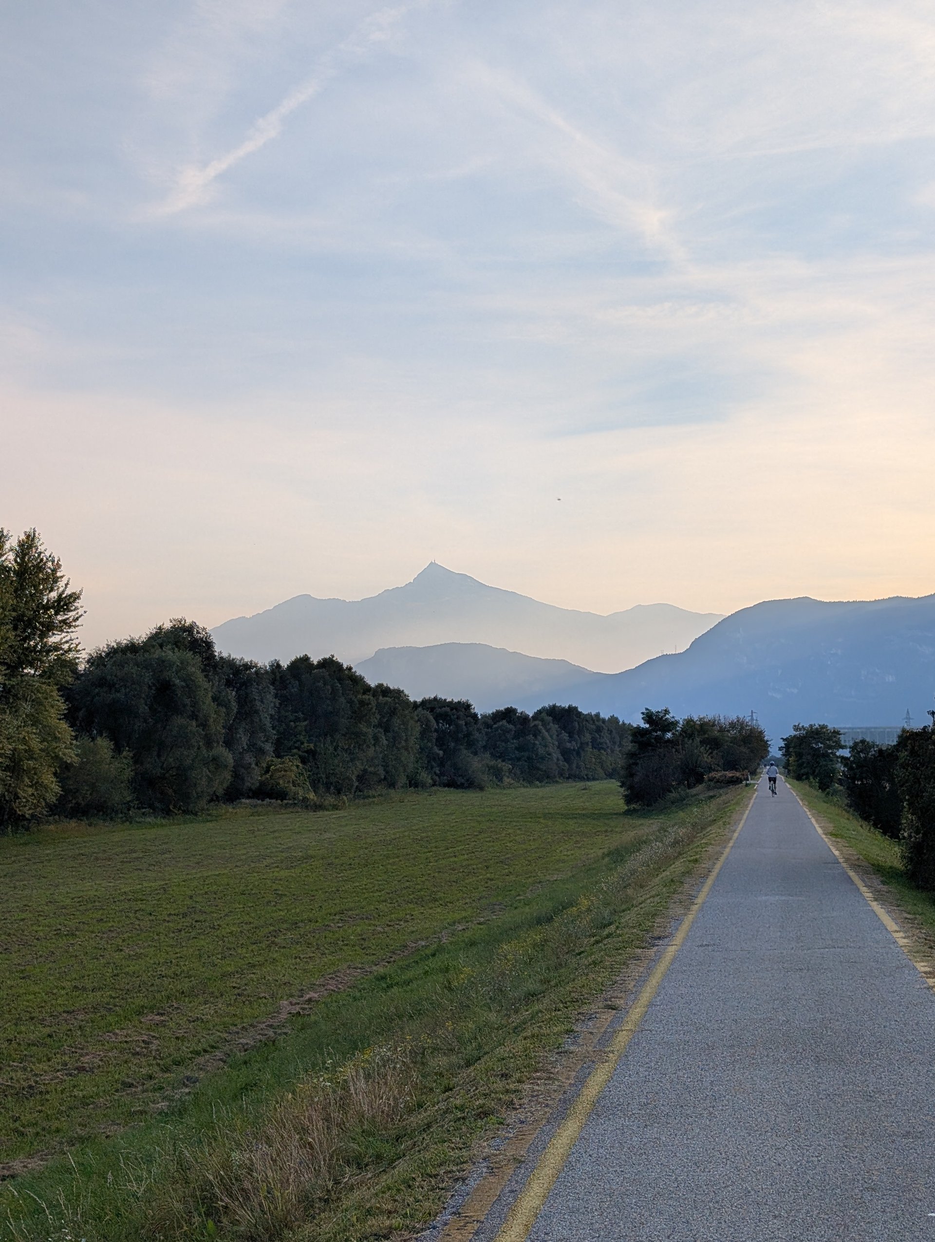 A cycle path leading toward hazy mountain peaks