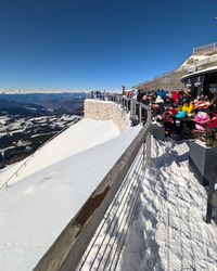 Outdoor terrace of Laurin Lounge with skiers relaxing and wide views in the background.