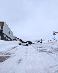 Close-up of the spacious Passo Fedaia parking area with cars and snowy landscape.
