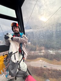 David in the gondola with the ski resort and rainy weather in the background.