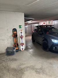 Snowboarding gear leaning against the wall next to our Subaru as we are getting ready to drive to Cavalese, Val di Fiemme.
