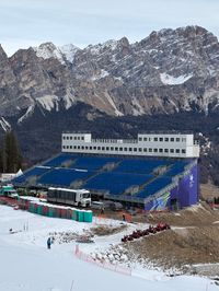 Olympic grandstand construction in Cortina with minimal snow on surrounding slopes