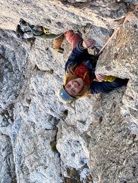 Daysi smiling mid-pitch while climbing Via del Gracchio in the Dolomites.
