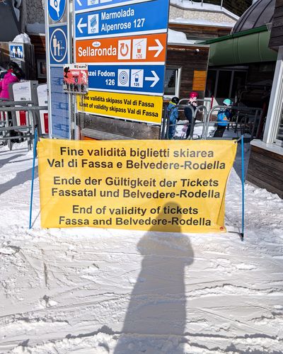 Slow panoramic sweep over wide sunny slopes at Carezza Ski with the Dolomites on the horizon.