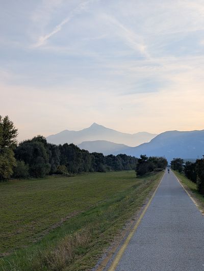 A cycle path leading toward hazy mountain peaks