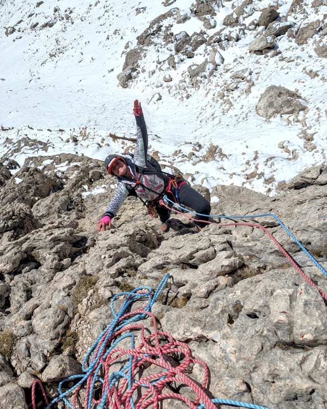 Climber reaching the first bolted belay at the top of pitch one.