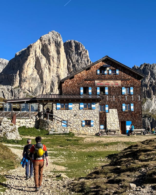 Hikers approaching Rifugio Roda di Vael beneath the Catinaccio peaks.