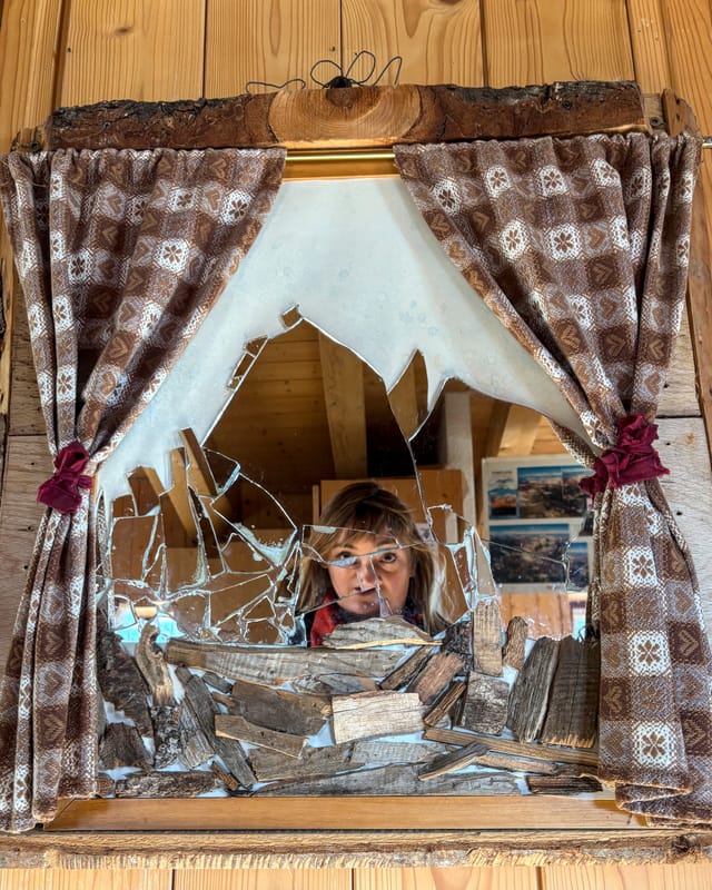 A visitor reflected in a handmade mountain-shaped mirror inside Rifugio Roda di Vael.
