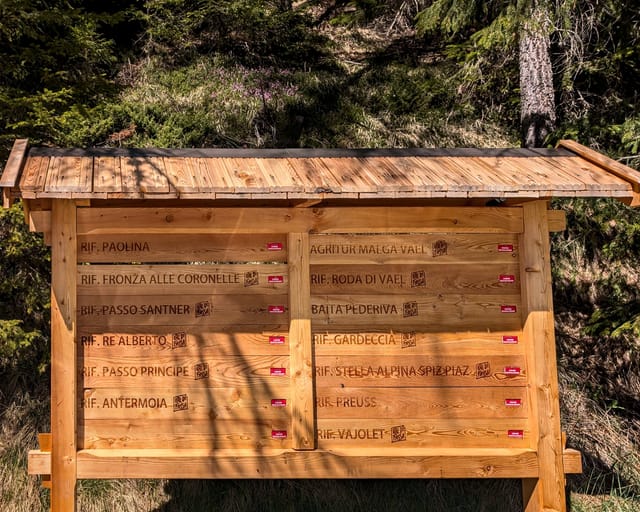 Wooden trailhead board listing Rifugio Roda di Vael and other Val di Fassa rifugi as closed.