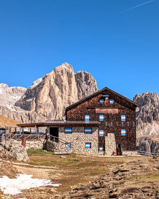 Rifugio Roda di Vael beneath the Catinaccio peaks on a clear spring day.