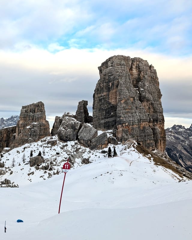 The Cinque Torri rock towers above a snowy piste.